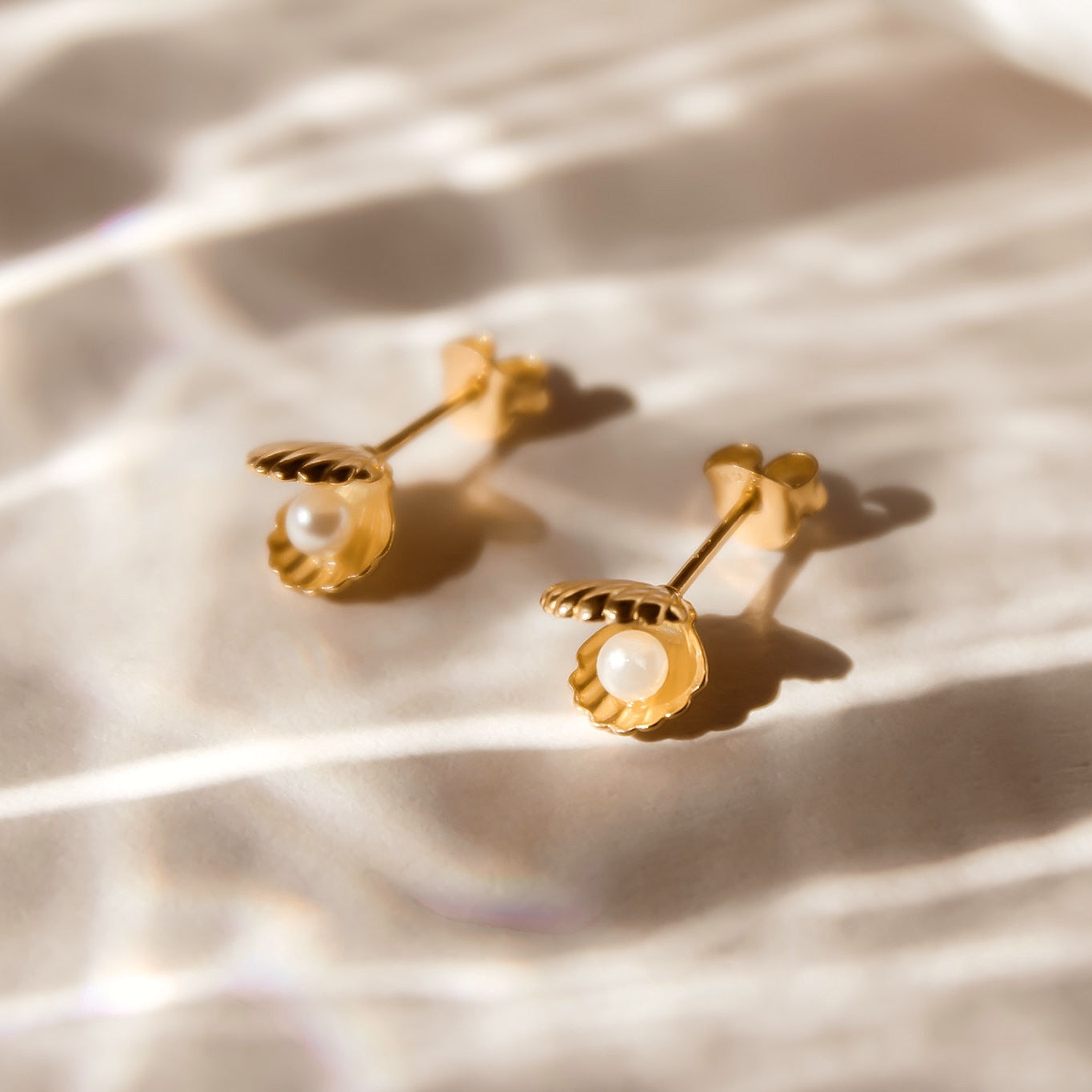 Goldene Muschel Ohrstecker mit einer winzigen weißen Perle verziert.